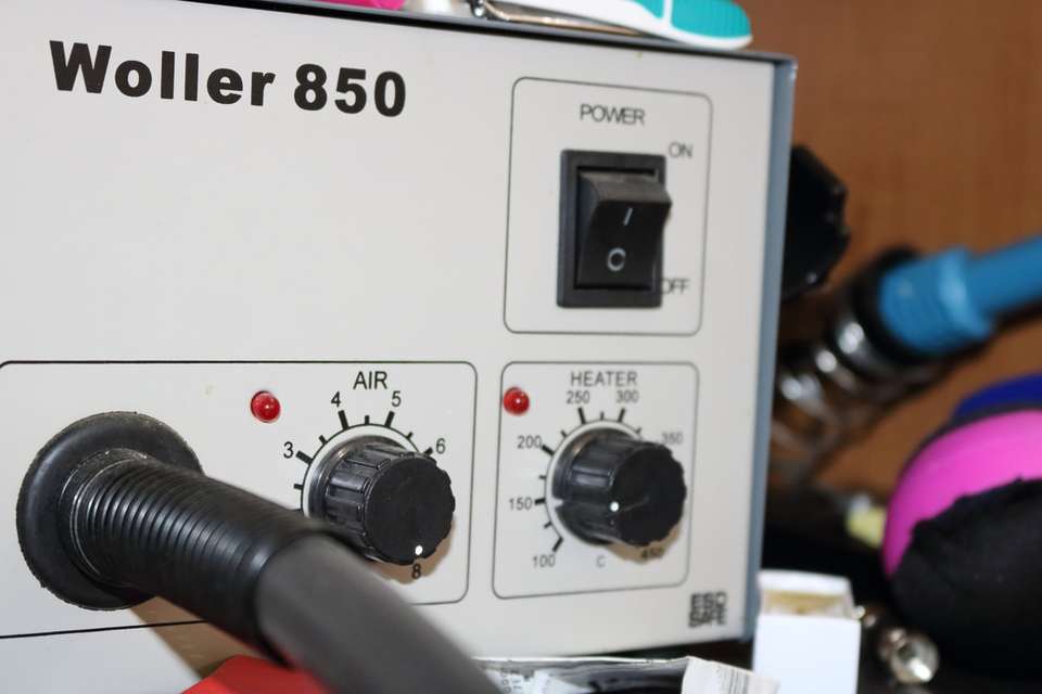Repair bench with a microscope, soldering tools, and a phone opened for board-level work